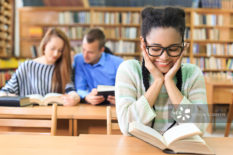 在图书馆看书的微笑高中生图片素材