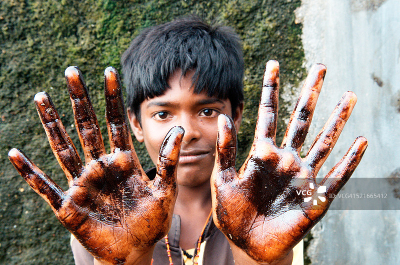 男孩展示因集装箱船在印度孟买相撞而浸油的手掌图片素材