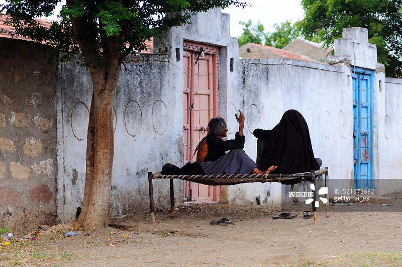坐在印度古吉拉特邦安贾尔附近明迪亚达房屋外的老年妇女图片素材