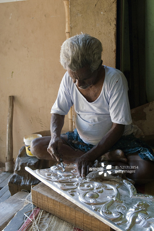 在印度卡拉库迪，泰米尔纳德邦，男子制作银卡瓦萨姆覆盖寺庙雕刻图片素材