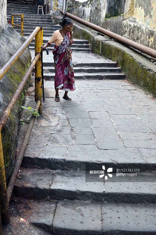 老妇人走下通往印度孟买邦冈加的台阶图片素材