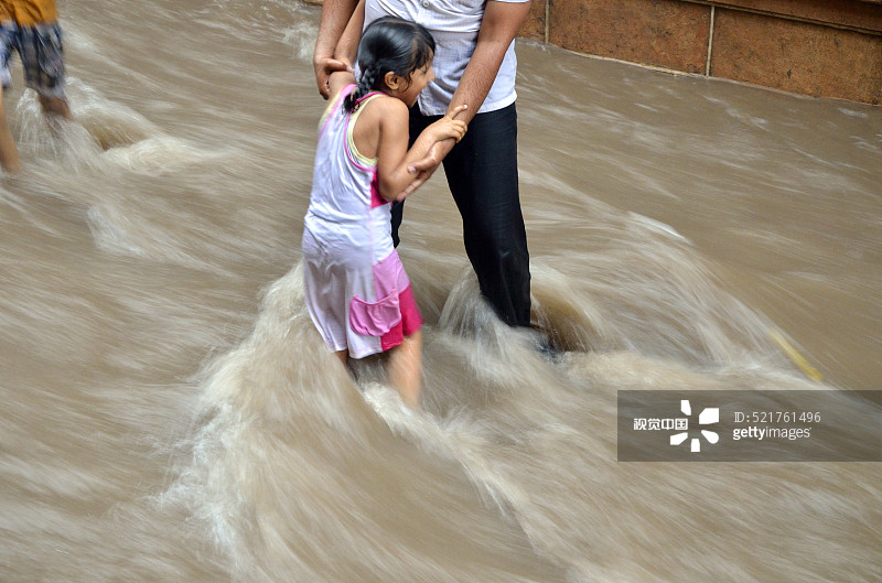 男人抱着女孩在季风的流水中，焦特布尔，拉贾斯坦邦，印度图片素材