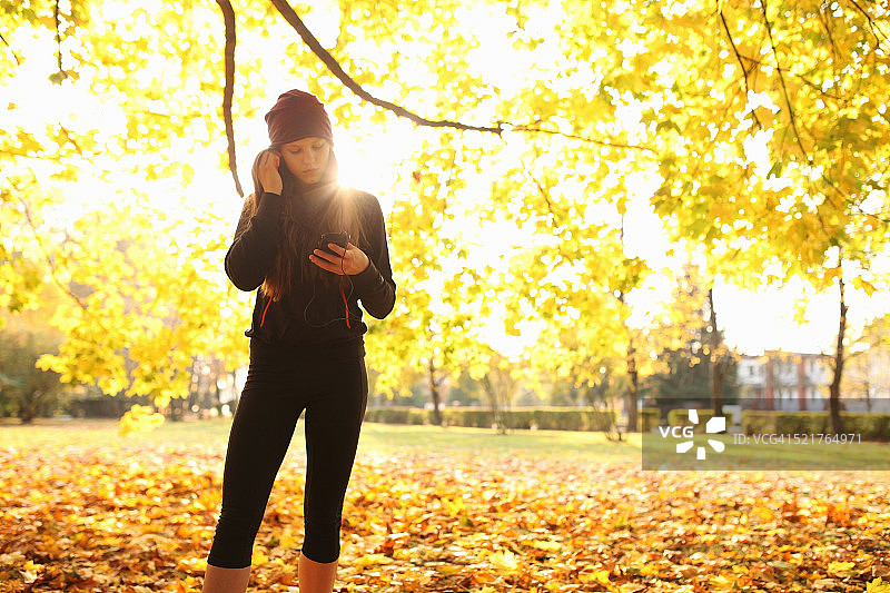 秋季，女孩在跑步时查看手机图片素材