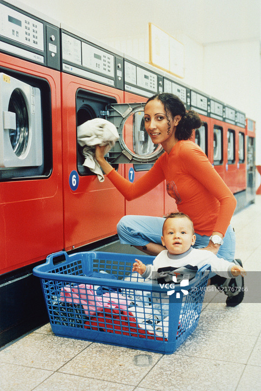 年轻的母亲和她的孩子在自助洗衣店图片素材
