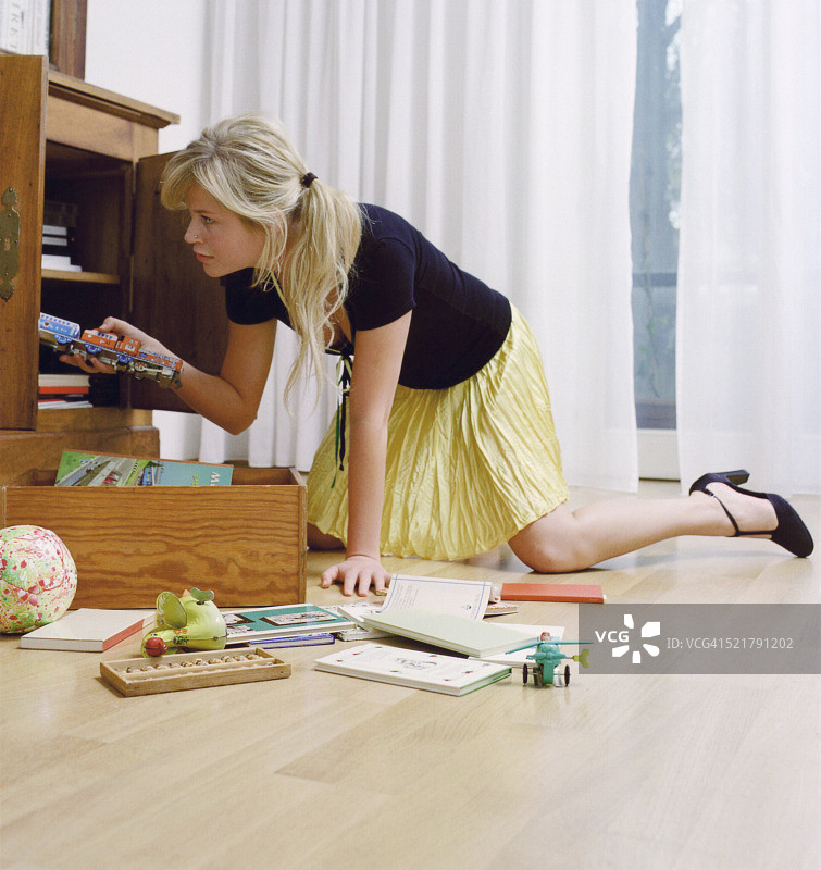 年轻女子将玩具放入柜中图片素材