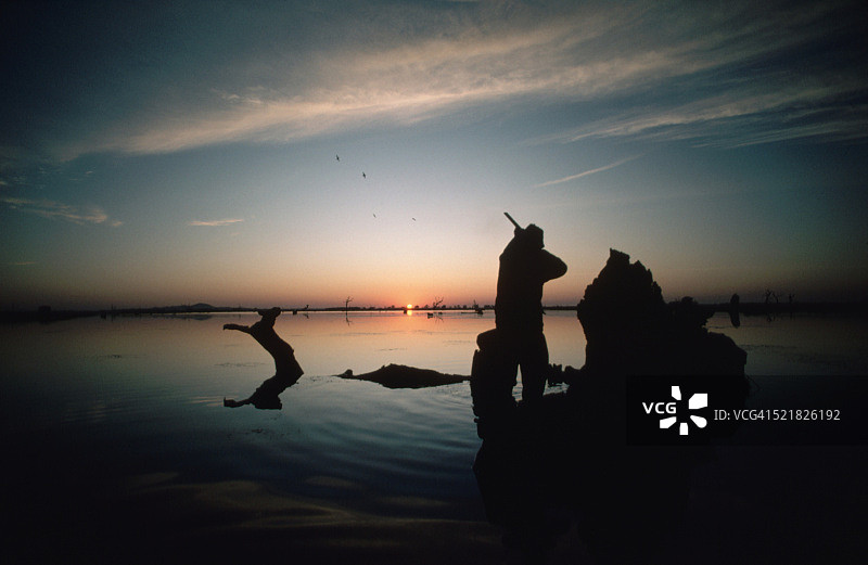 黎明时分湿地中的猎人剪影图片素材