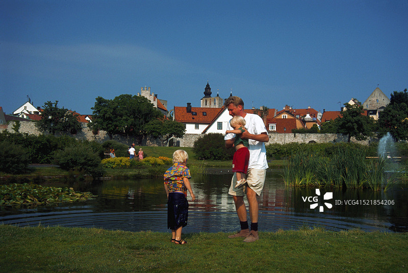 男子和孩子们在池塘边图片素材