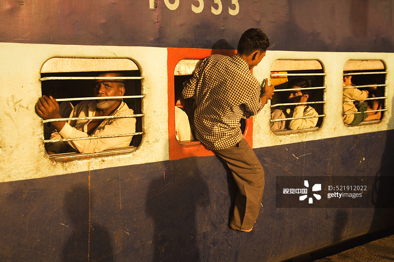 男人从印度古吉拉特邦苏拉特火车站的火车紧急窗口出来图片素材