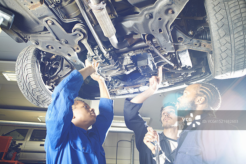 三位大学生在车库工作室抬头看车图片素材
