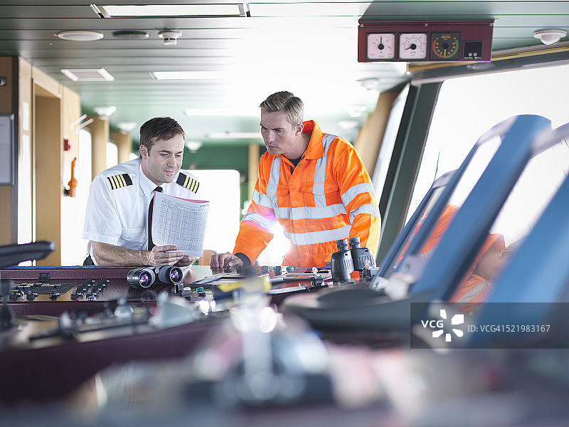 船长和工人在舰桥上讨论笔记图片素材