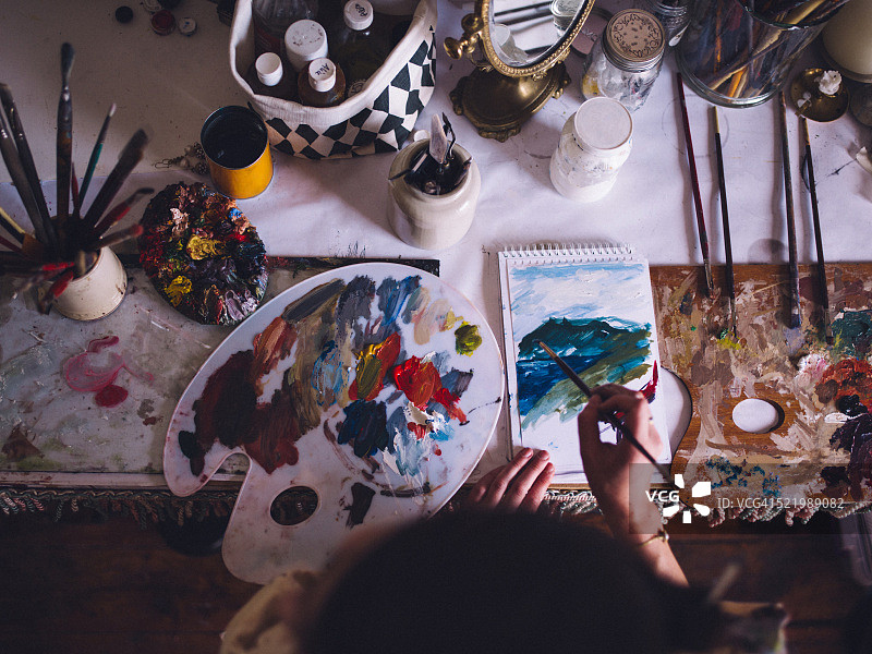 艺术家用调色板和鲜艳的色彩在纸上绘画图片素材