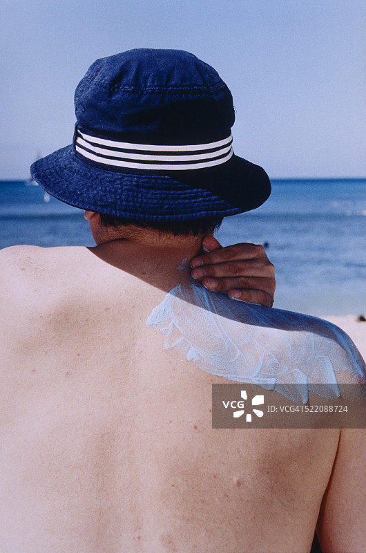 戴着遮阳帽涂抹防晒霜的男人图片素材