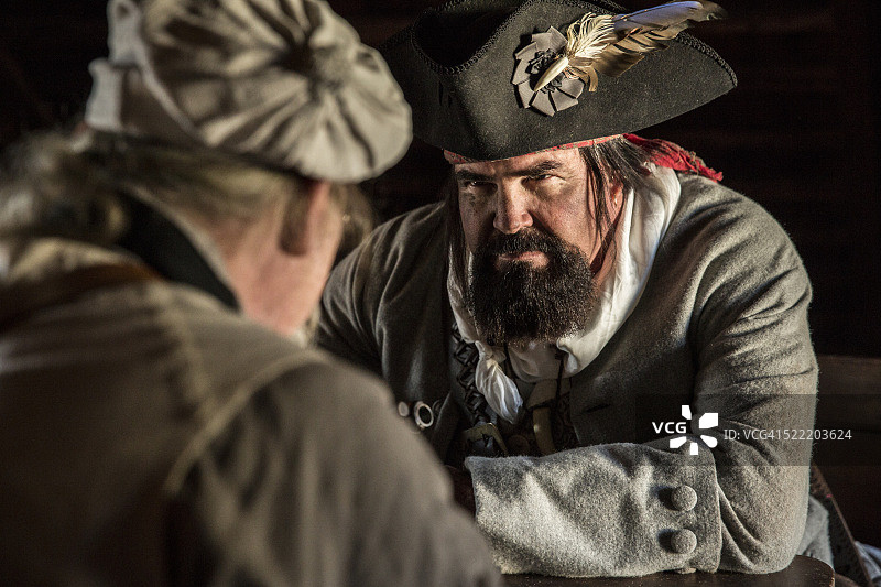 在旧阁楼里，两个具有历史意义的真正海盗在桌旁交谈图片素材