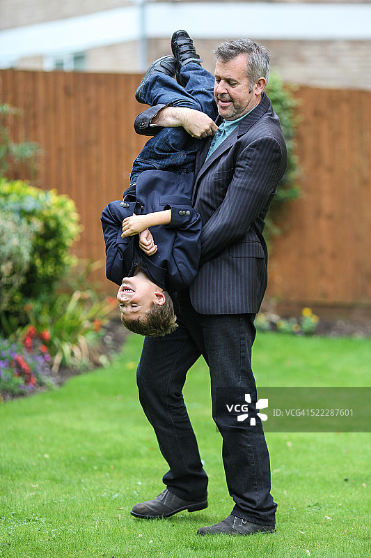 父亲在花园里把儿子倒过来抱图片素材