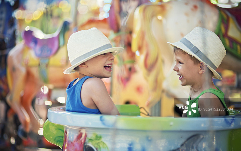小兄弟在旋转木马上玩耍图片素材