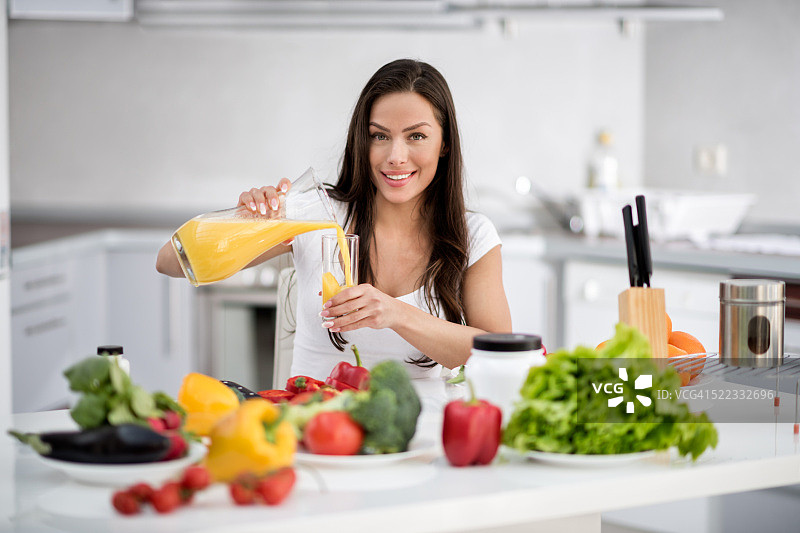 在厨房喝橙汁的女人图片素材