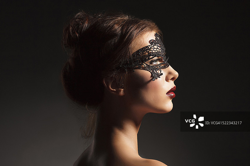 戴着黑色蕾丝面具的年轻美女图片素材