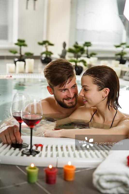快乐的夫妇在热水浴缸里喝葡萄酒图片素材