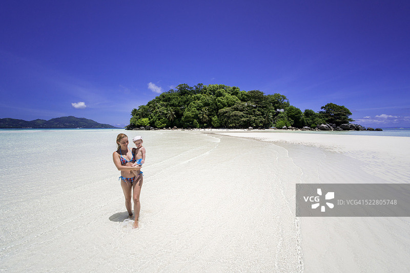 微笑的母亲和她的儿子在塞舌尔的海上行走图片素材