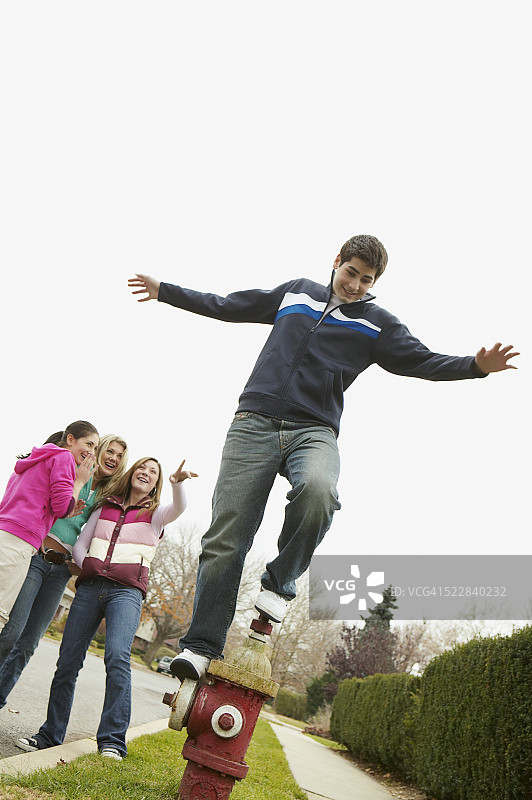 女孩们看着站在消防栓顶端的男孩图片素材