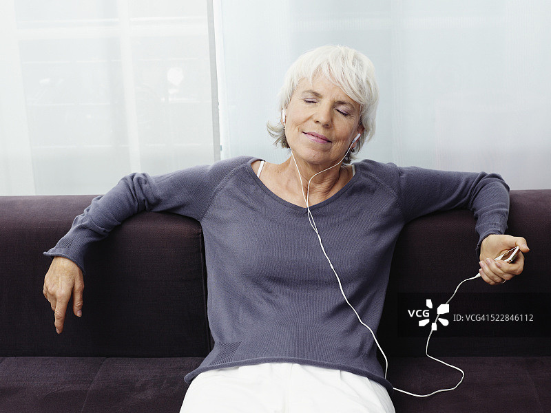 在沙发上使用MP3播放器的女人图片素材