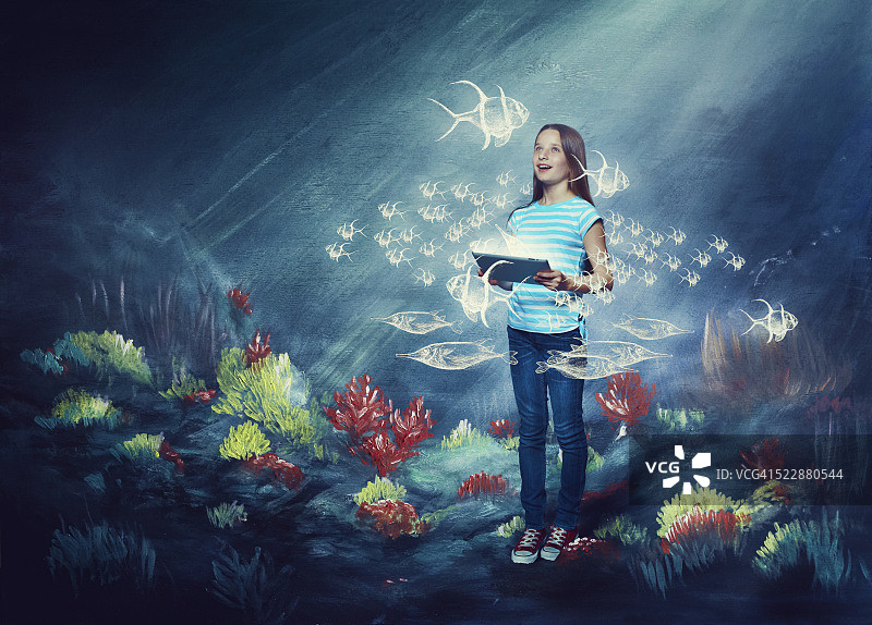 穿着完整的年轻女孩（10-12岁）在水下使用数位平板电脑的合成图像图片素材