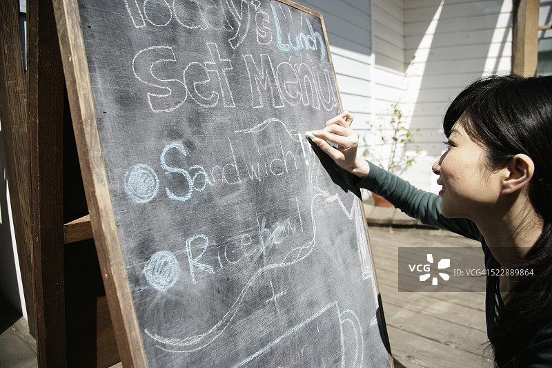 女人在三明治板上写午餐菜单图片素材