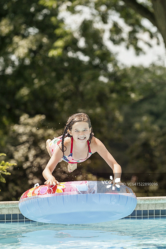 跳入泳池，拿着充气圈的女孩（8-9岁）图片素材