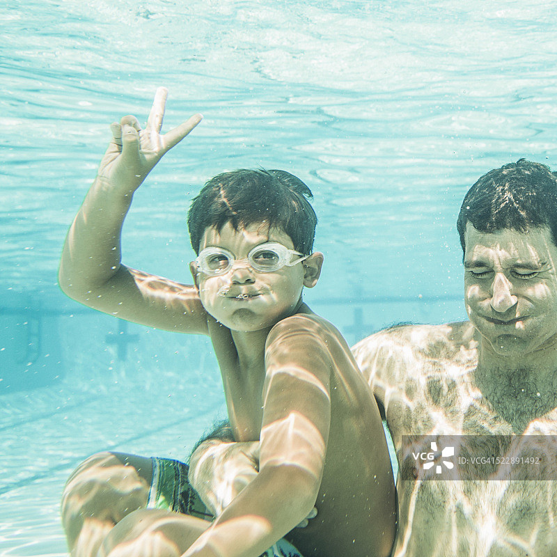 父亲和儿子(6-7岁)在游泳池中享受水下乐趣图片素材