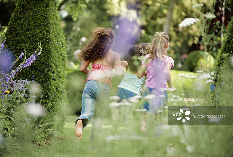 在花园里奔跑的三个女孩的背影图片素材