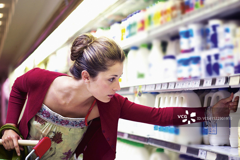 女人在超市的乳制品区拿出一罐牛奶图片素材