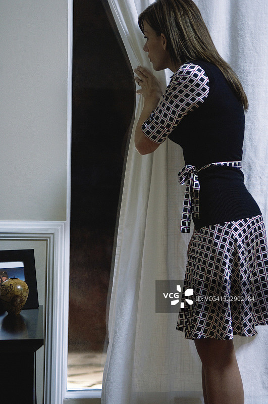 女人小心地向窗外看图片素材