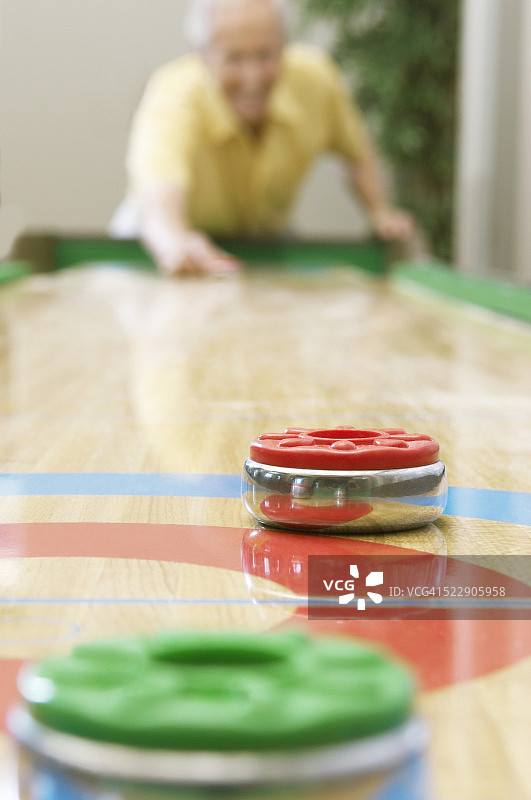 男人玩桌上冰壶球图片素材