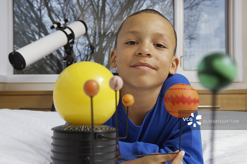 在床上用望远镜和天文仪器的男孩图片素材