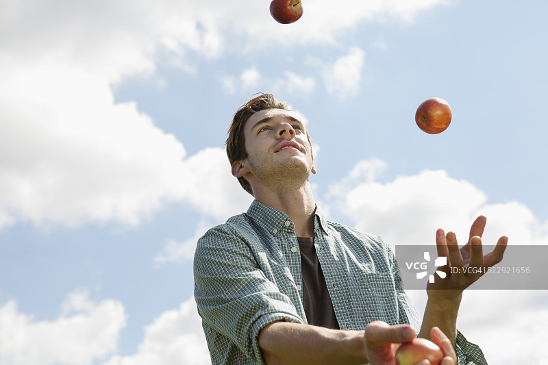 在阴天玩苹果的英国青年图片素材