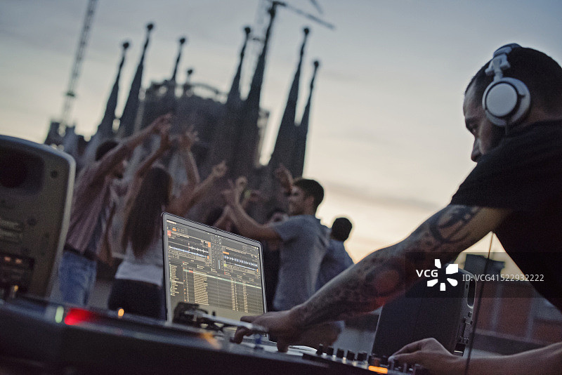 唱片骑师在屋顶露台上表演，一群人在背景中跳舞图片素材