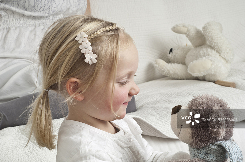 抱着毛绒玩具，背景是怀孕母亲的女孩图片素材