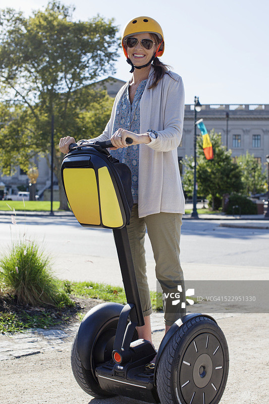 微笑的女人在城市中骑平衡车图片素材