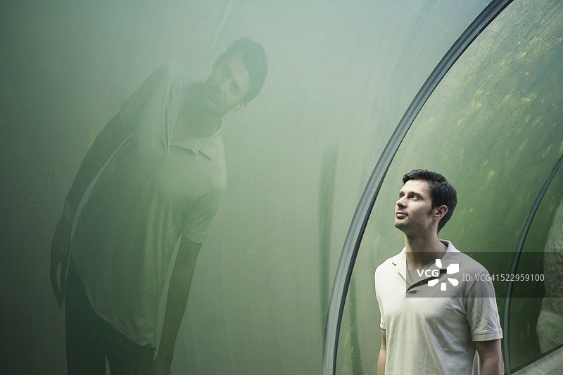在水族馆玻璃中看倒影的男人图片素材