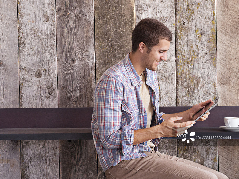 坐在咖啡馆里，拿着平板电脑的男人图片素材