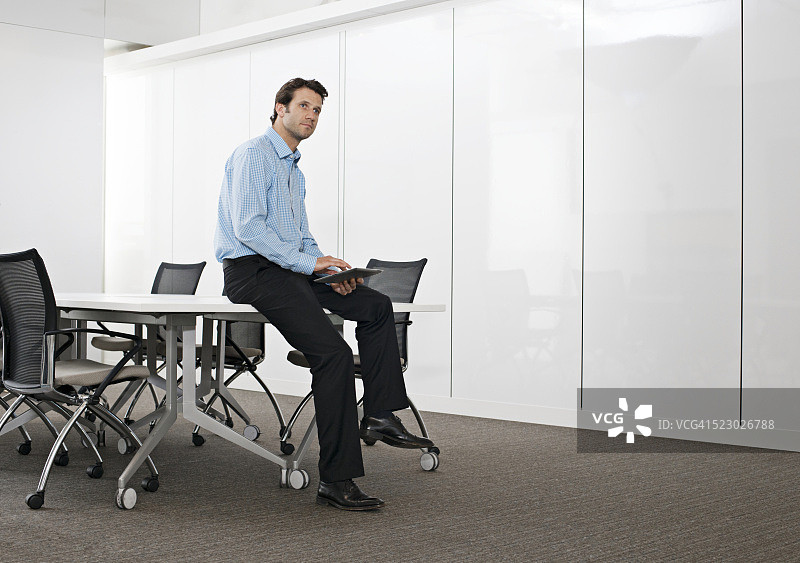 坐在会议室里手持平板电脑的商人图片素材