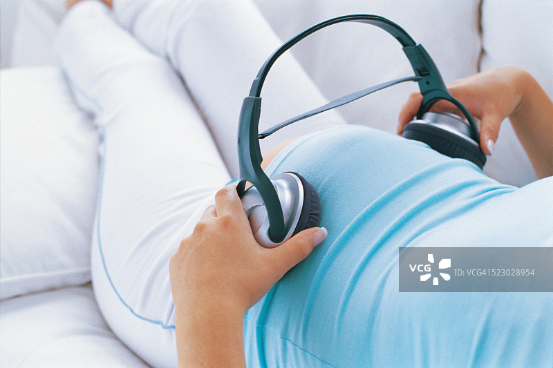 孕妇手拿耳机放在肚子上图片素材