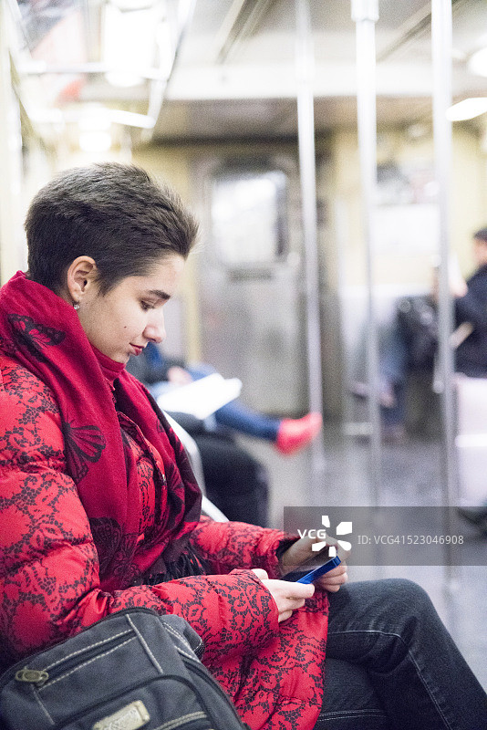 年轻女人在纽约市地铁使用智能手机图片素材