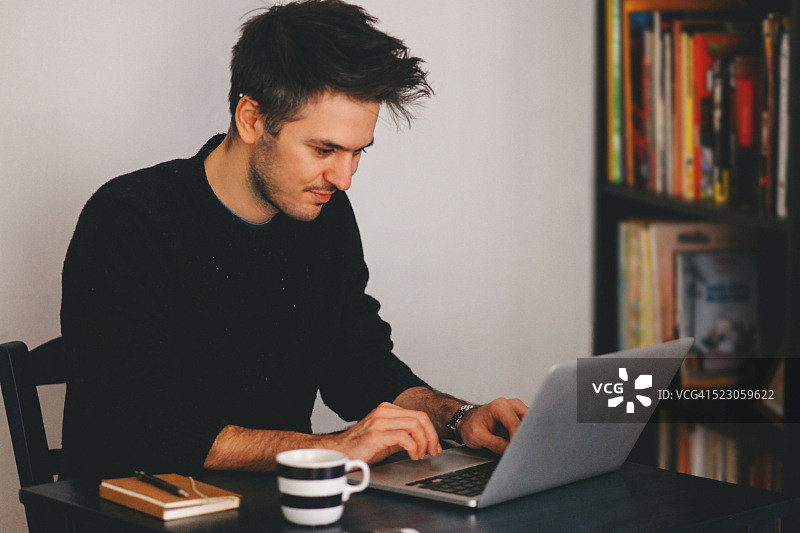 年轻男人在笔记本电脑上打字图片素材