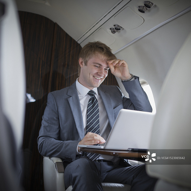 在喷气式飞机上使用笔记本电脑的商人图片素材