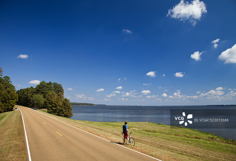 年轻健壮的男人在阳光明媚的日子里骑着公路自行车，美国密西西比州纳奇兹图片素材