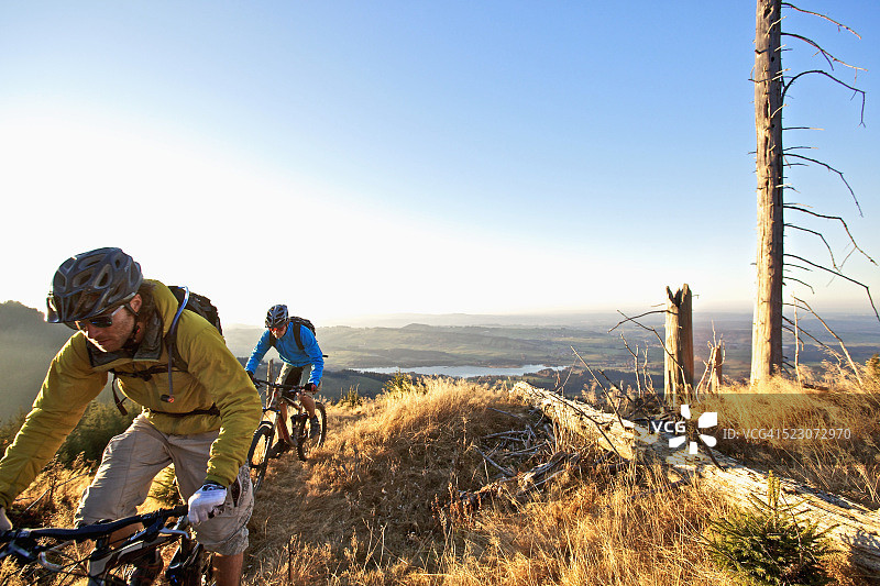在德国加米施-帕滕基兴阿尔卑斯山小路上骑自行车的两人图片素材
