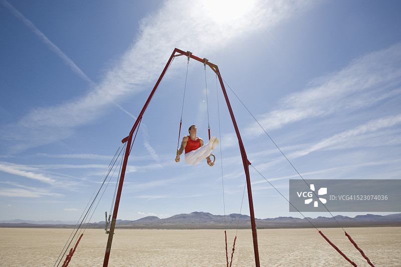 在沙漠中进行吊环表演的体操运动员图片素材