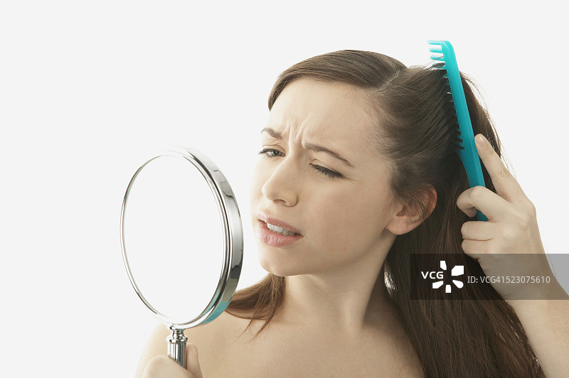 年轻女子梳头并手持镜子图片素材