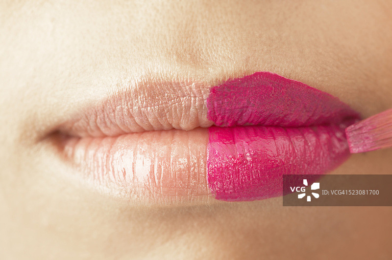 年轻女人在半张嘴上涂口红图片素材